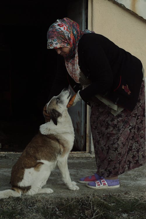 Woman in Floral Hijab Holding Short Coated Dog