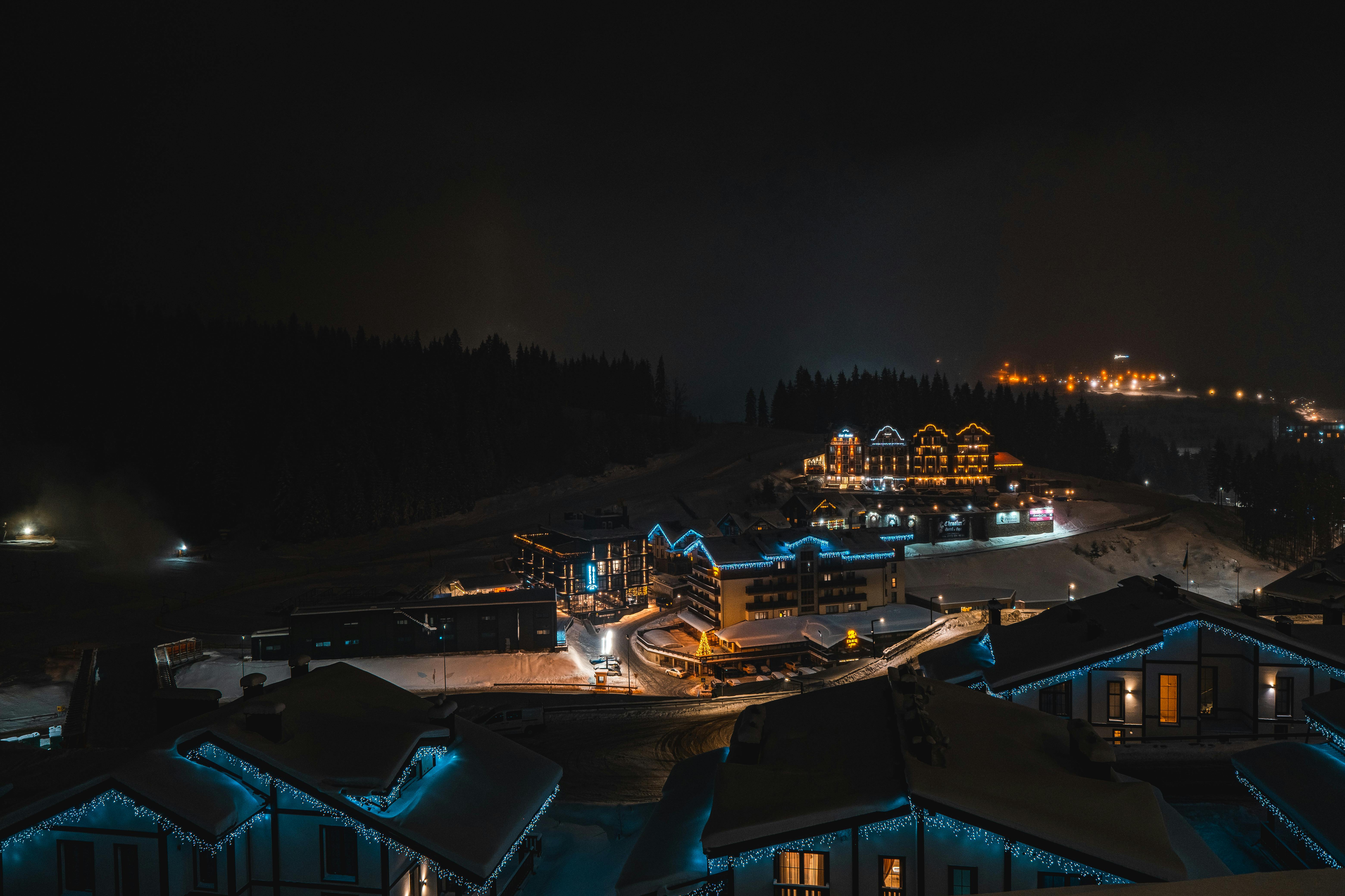 Idyllic winter night scene with illuminated town buildings in Ukraine's snowy landscape.