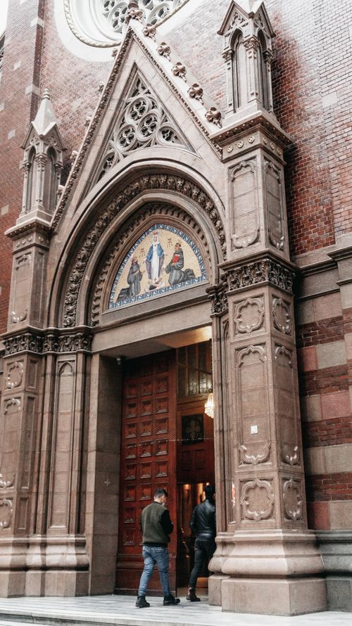 Free A beautiful Gothic church entrance captured with intricate stonework and visitors entering. Stock Photo
