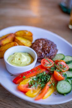 Grilled beef with vibrant vegetables and sauce on a white plate for a delicious meal.