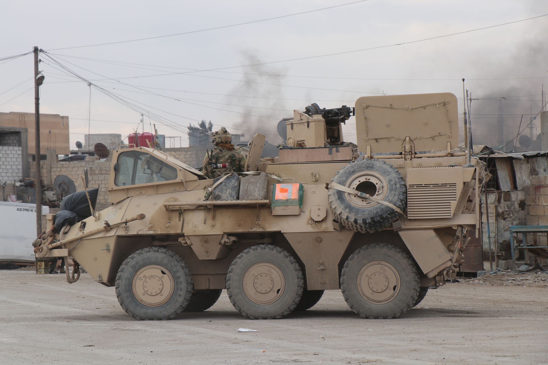 Un véhicule militaire sur une route poussiéreuse au crépuscule