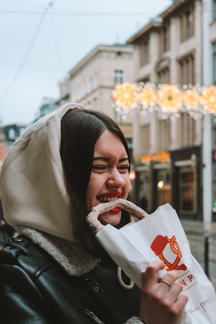 Woman In Black Leather Jacket Biting A Pretzel 