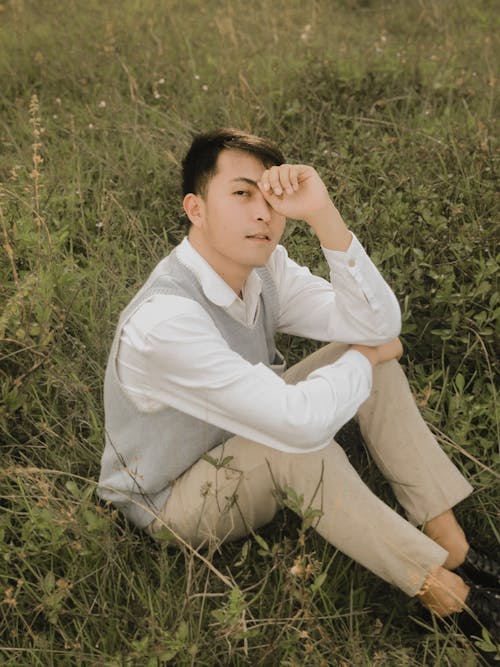 Young Man in Elegant Clothes Sitting on Field