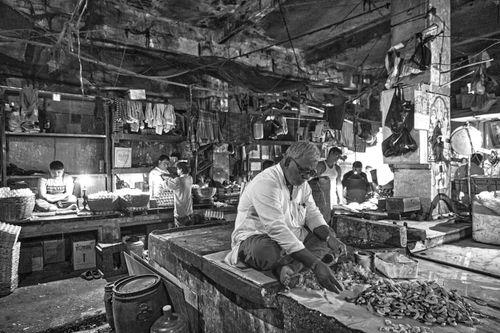 Free A vendor at a bustling indoor market selling goods in a black and white setting. Stock Photo