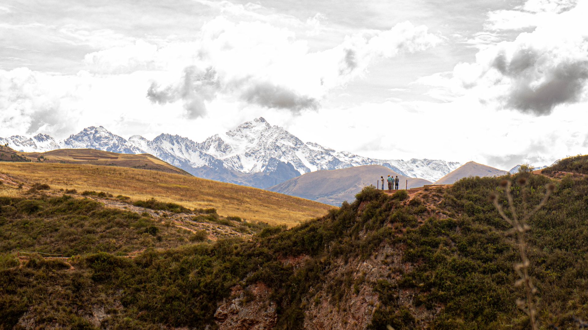 Breathtaking mountain landscape with tourists on ridge under a dramatic cloudy sky.