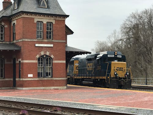 Black and Yellow Train on Rail Road Near Brown Concrete Building