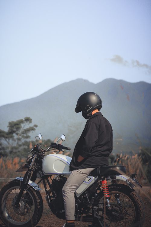 Free A motorcyclist in a black helmet pauses to enjoy a peaceful mountain view in Jawa Barat, Indonesia. Stock Photo