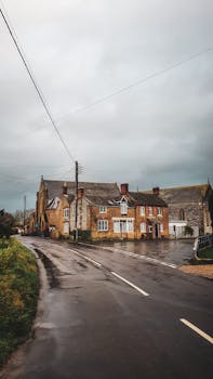Quaint stone houses along a wet countryside street, showcasing vintage architecture after rain.