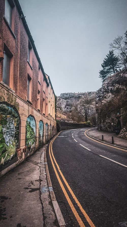 Free Curved urban street with murals on buildings, showcasing artistic vibrancy and calm ambiance. Stock Photo