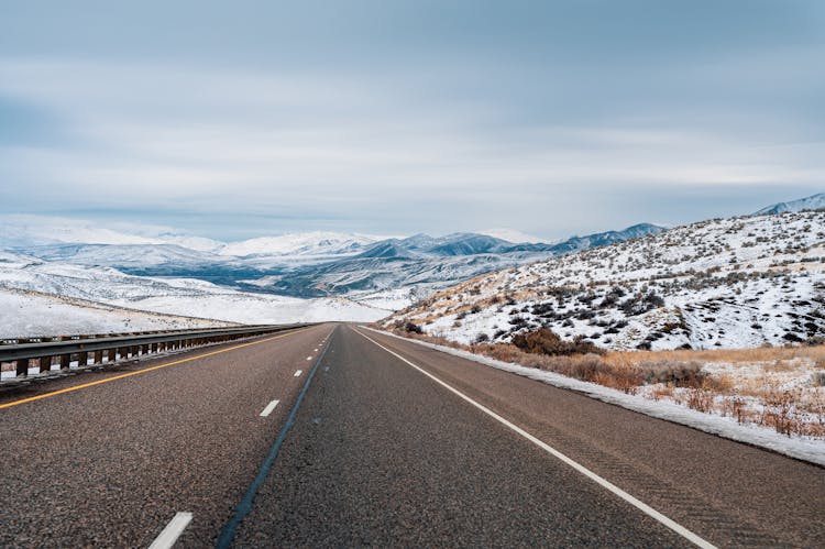 An Empty Road Across Snow Covered Mountains