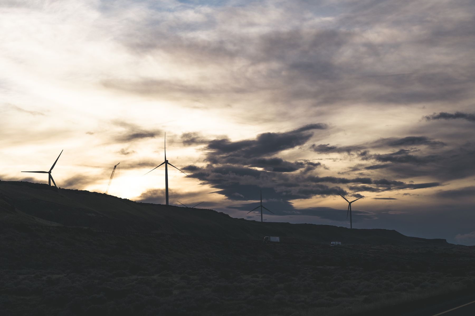 Wind turbines on a dark ridge beneath a heavy evening sky — photo by Brett Sayles on Pexels