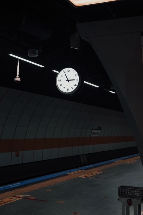 Free A modern train station in Istanbul featuring a prominently displayed clock with a dimly lit platform. Stock Photo