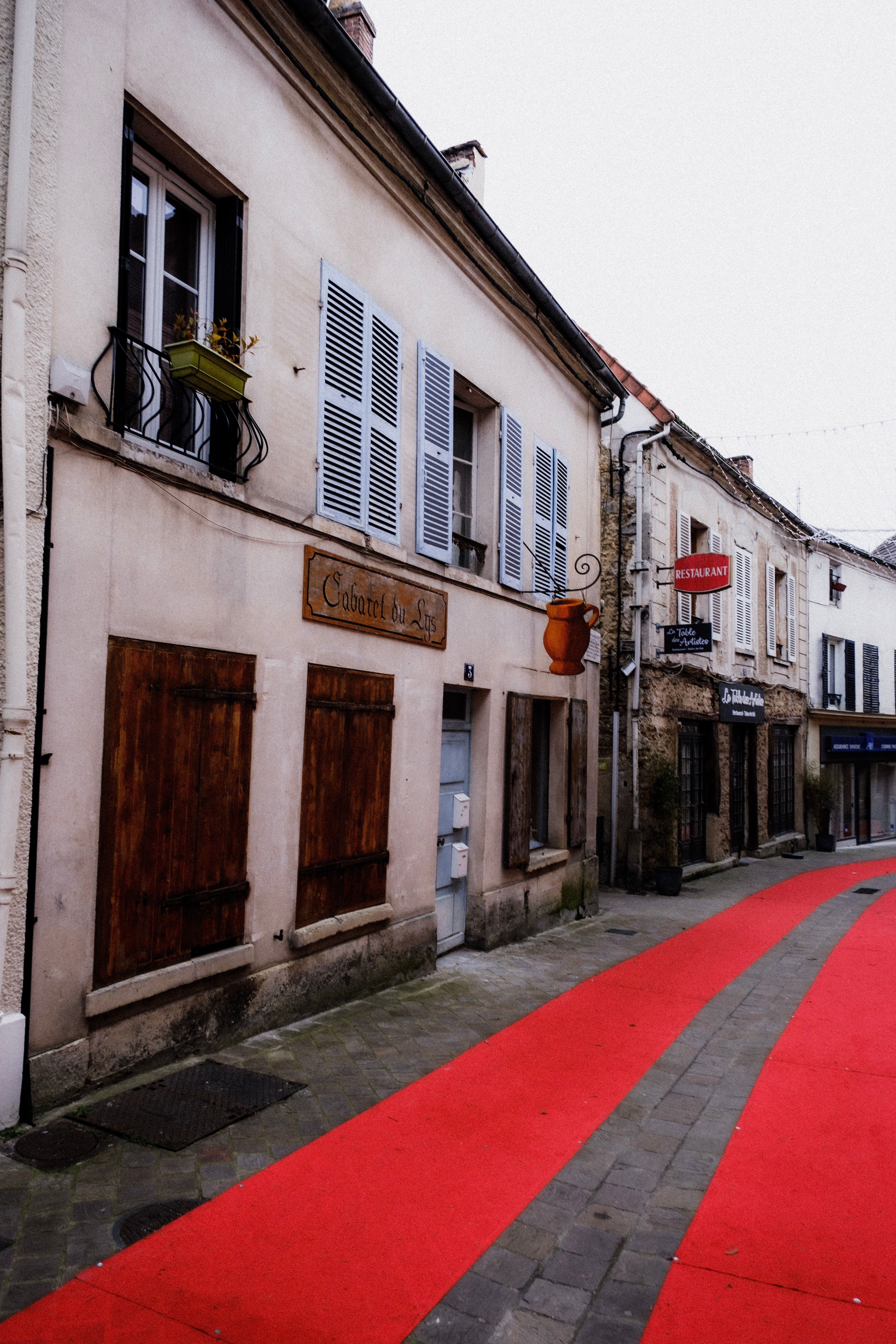 Quaint urban street with historic facades and a vibrant red pathway, perfect for exploring.