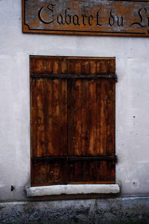 Free A rustic wooden door against a white wall with vintage signage above. Stock Photo