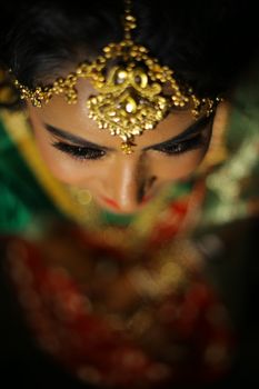 Close-up photo of an Indian bride in traditional attire with intricate gold jewelry.