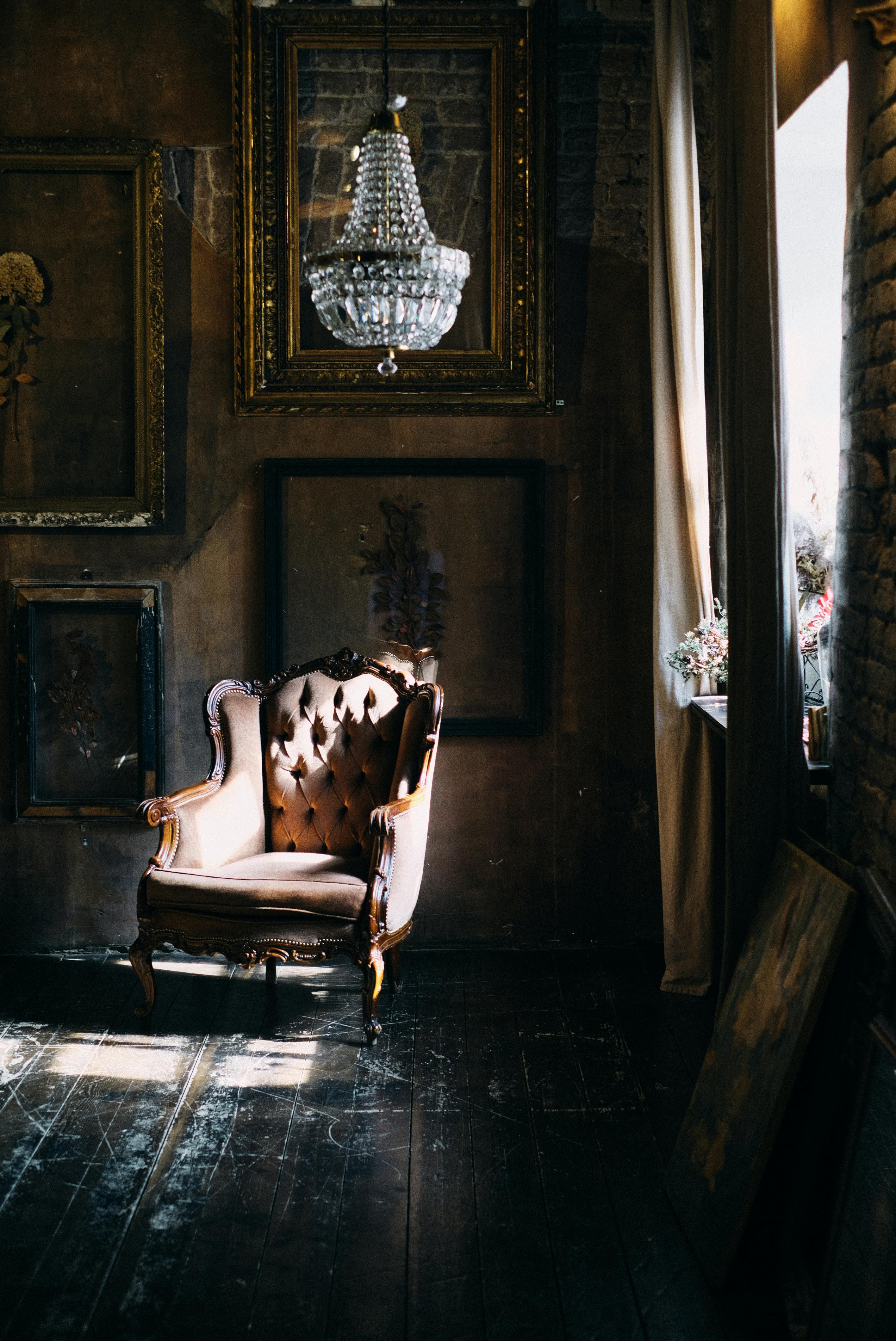 Luxurious vintage armchair bathed in soft light beneath a crystal chandelier in a richly decorated room.
