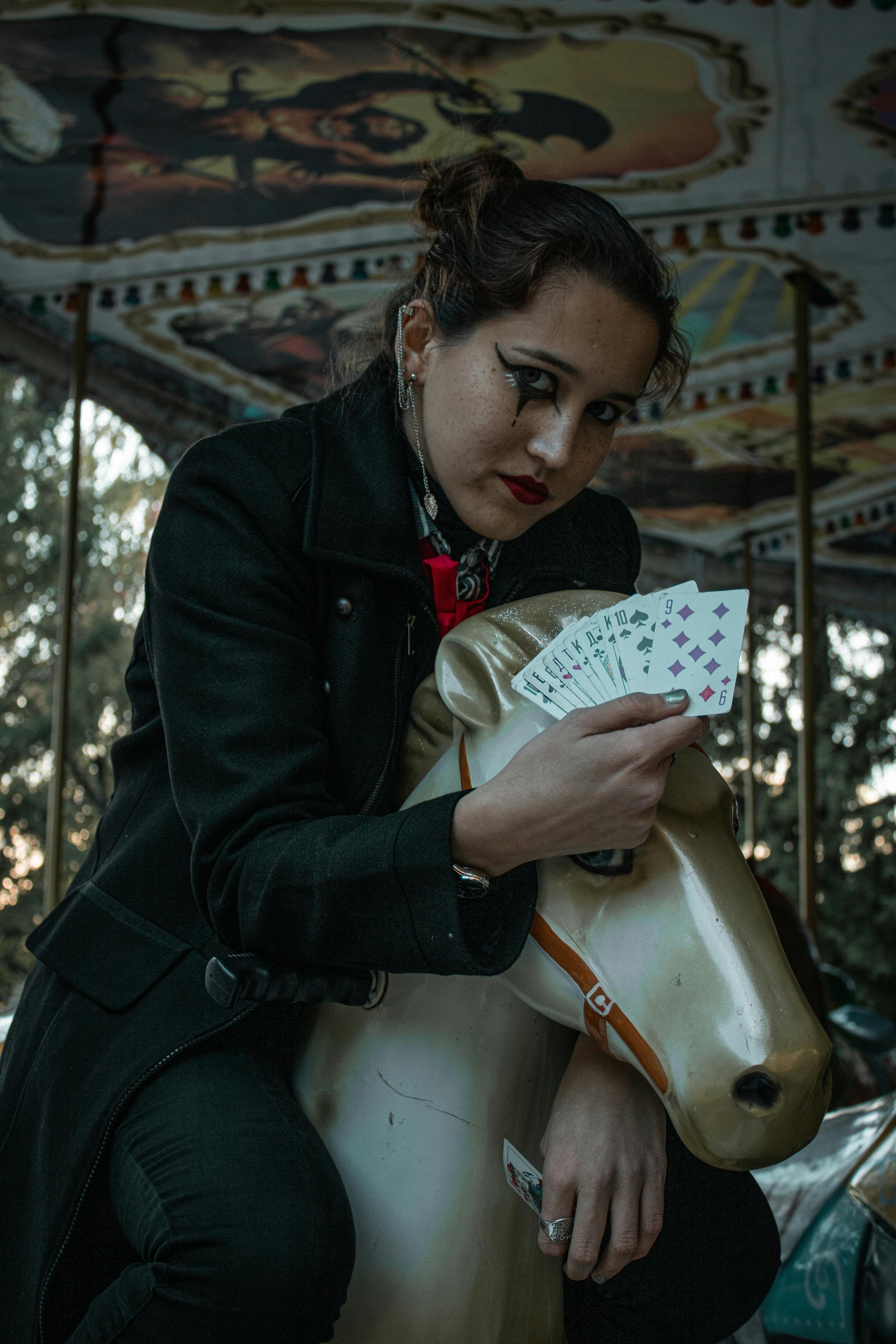 Woman in Black Jacket Riding on a Carousel Holding a Playing Cards ...