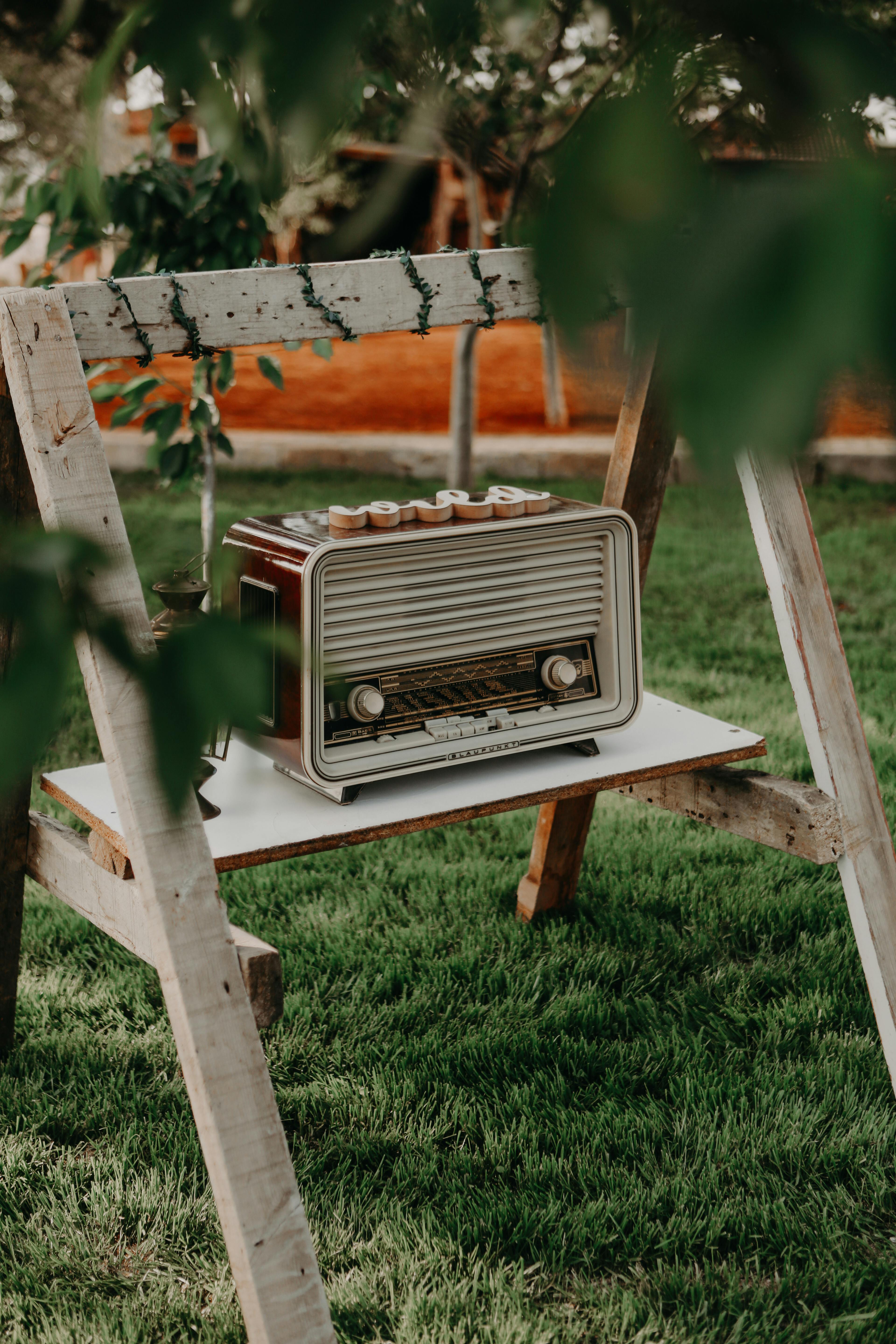 A retro radio placed on a wooden easel in a garden setting, evokes nostalgia and charm.