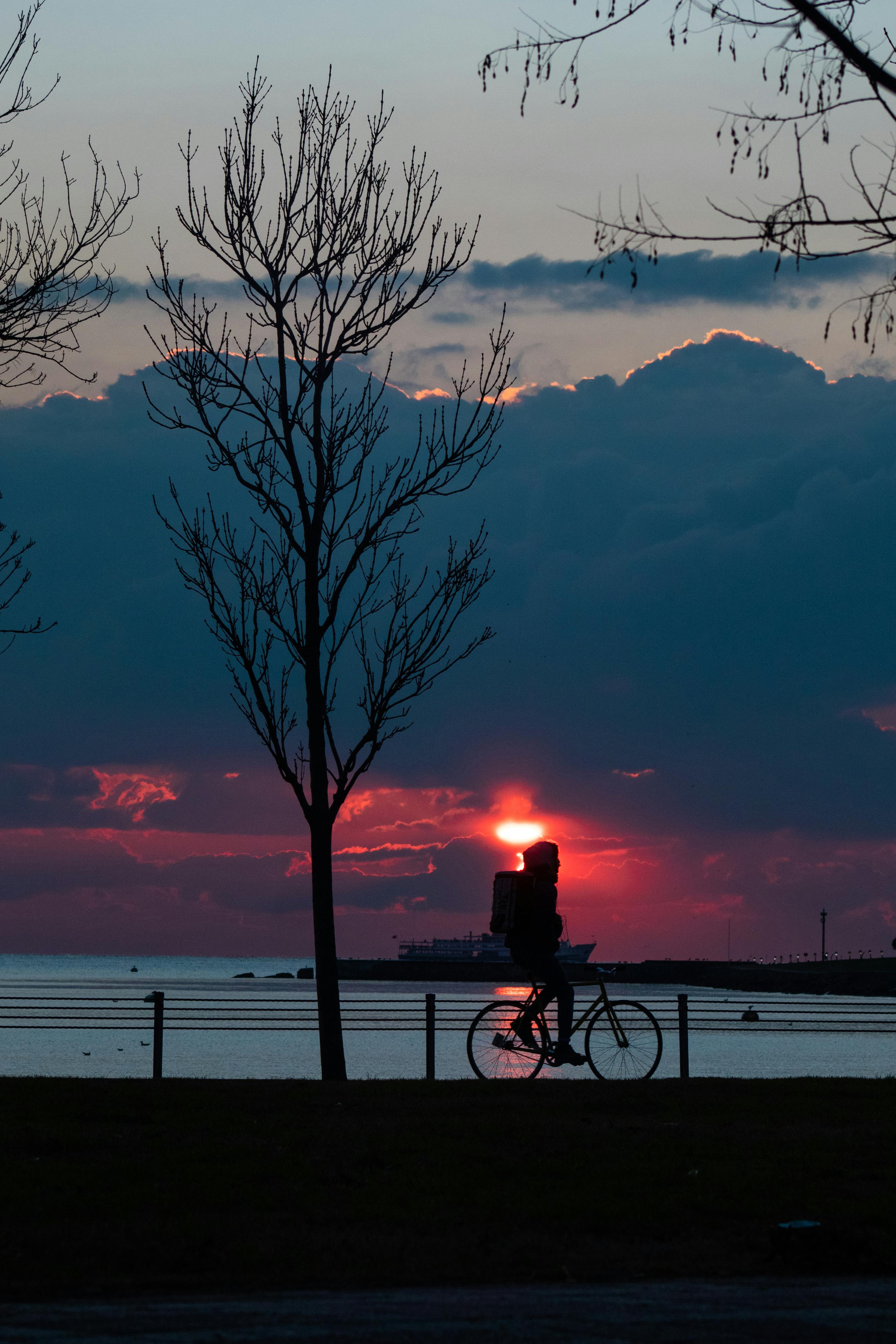 Cyclists riding along East Coast Park coastal path with Singapore city skyline in the background at sunrise