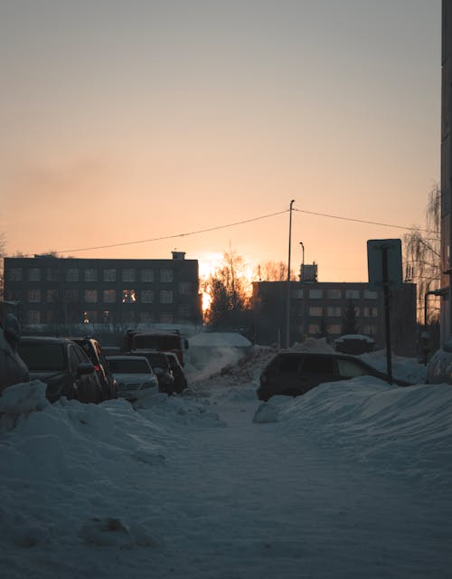 Cars on Snow Covered Ground Near Buildings