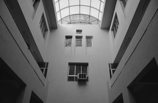 Black and white architectural view of an indoor atrium featuring a glass skylight.
