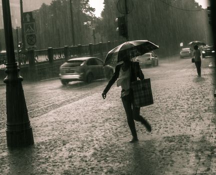 A woman with an umbrella walking on a rainy Moscow street, showcasing urban life.
