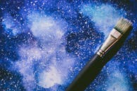 画笔放在纹理丰富的蓝色画布上，呈现出一幅充满活力的抽象水彩艺术