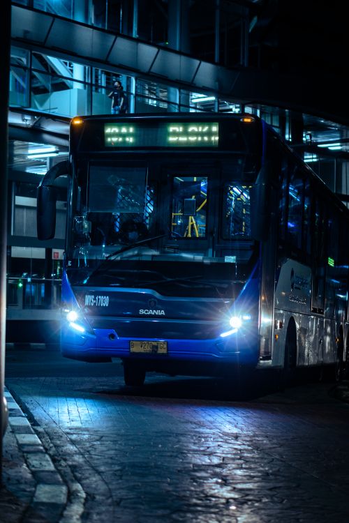 Free Blue public bus operating at night in South Jakarta, Indonesia urban environment. Stock Photo