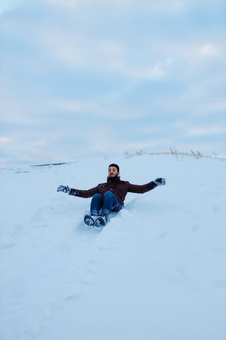 Man Sitting On The Snow With Outstretched Arms