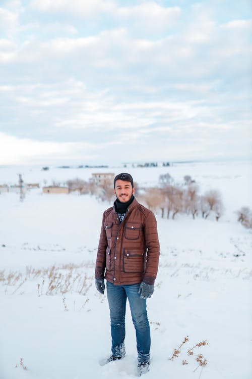 Free Man in Brown Jacket Standing on Snow Covered Hill Stock Photo