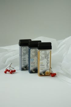 Aesthetic shot of three roll-on wax bottles with red berries on white fabric, creating a minimalist vibe.