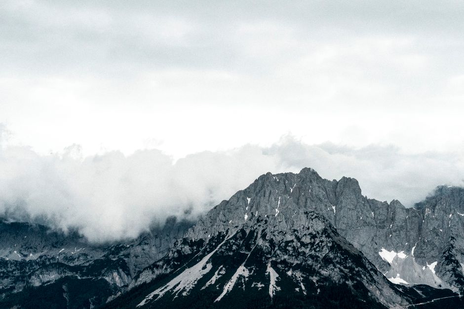 Grayscale view of Wilder Kaiser mountains with dramatic clouds casting shadows, Austria.