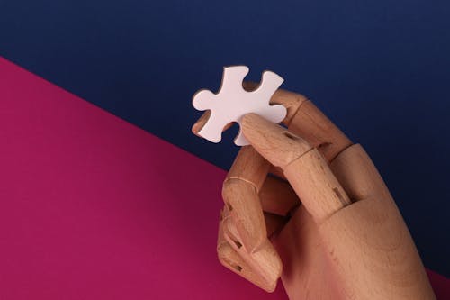 A Wooden Hand with a Jigsaw Puzzle Piece 