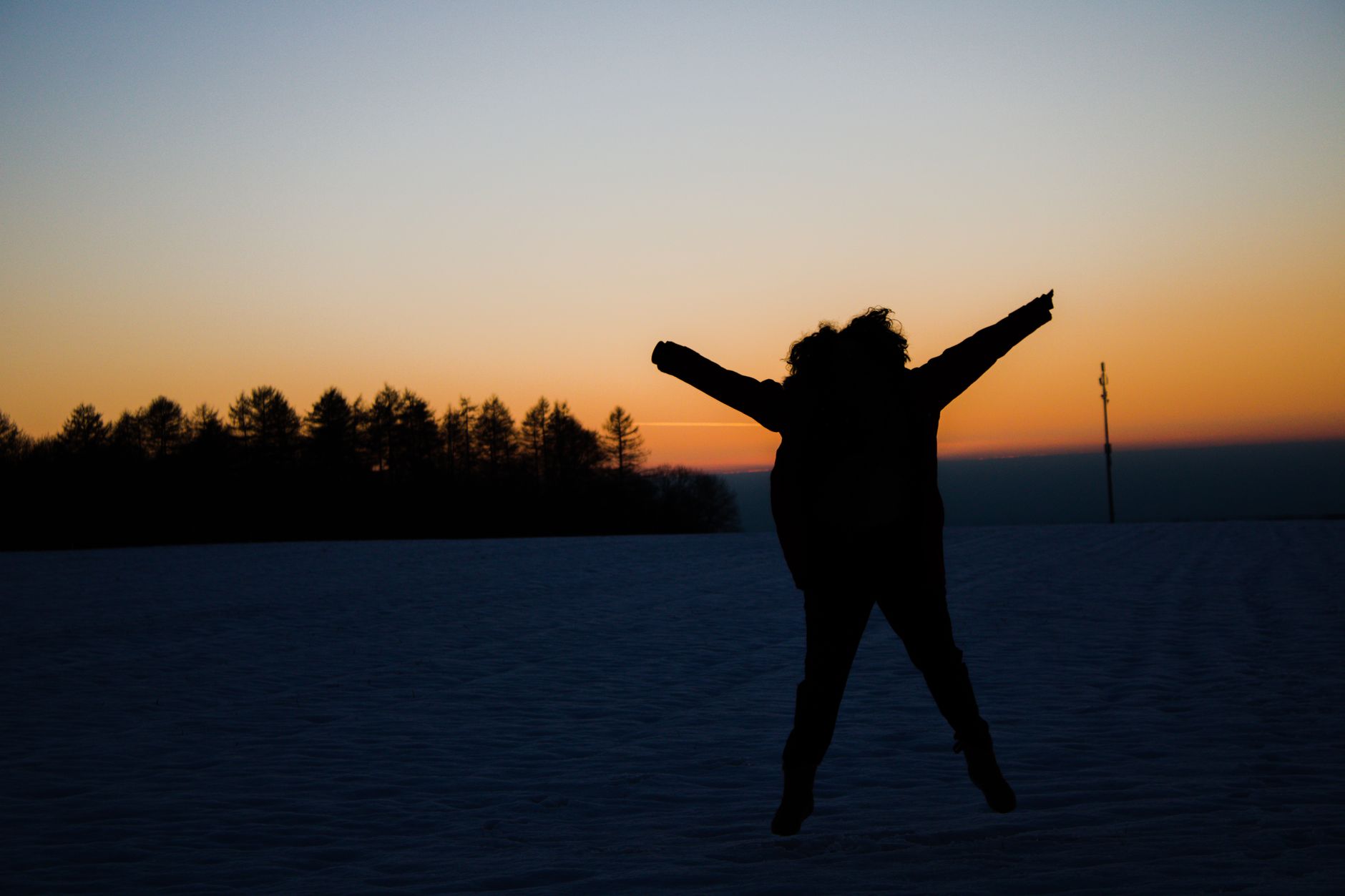 A silhouette captured against a vibrant winter sunset, showcasing the joy of nature.