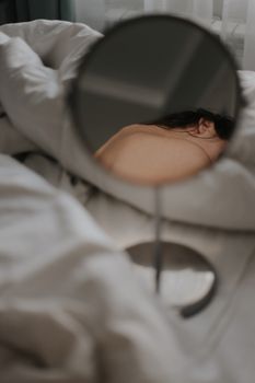 A woman's bare back is captured in a mirror creating a serene and intimate mood.