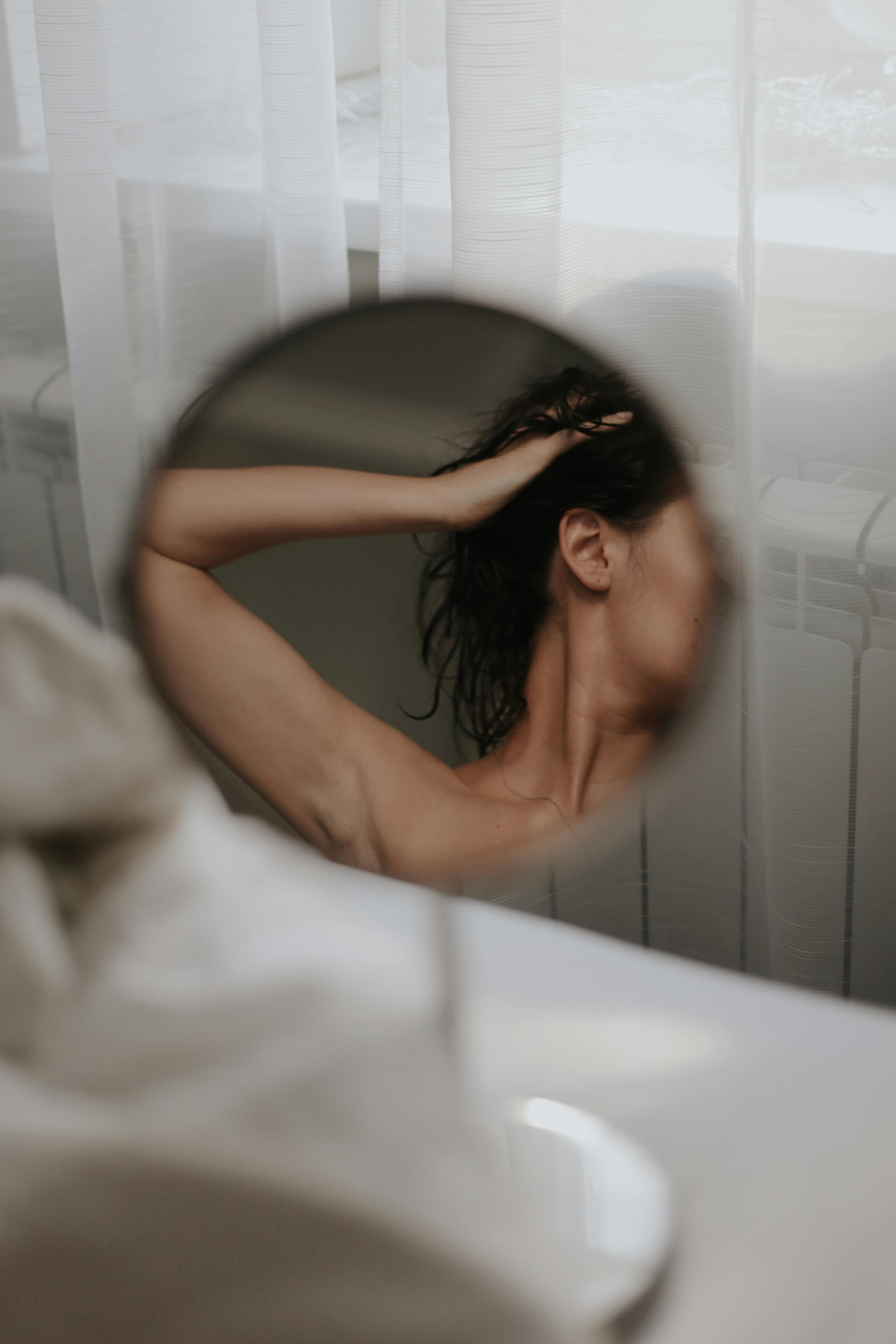 A thoughtful reflection of a woman in a mirror, displaying elegance and mystery.