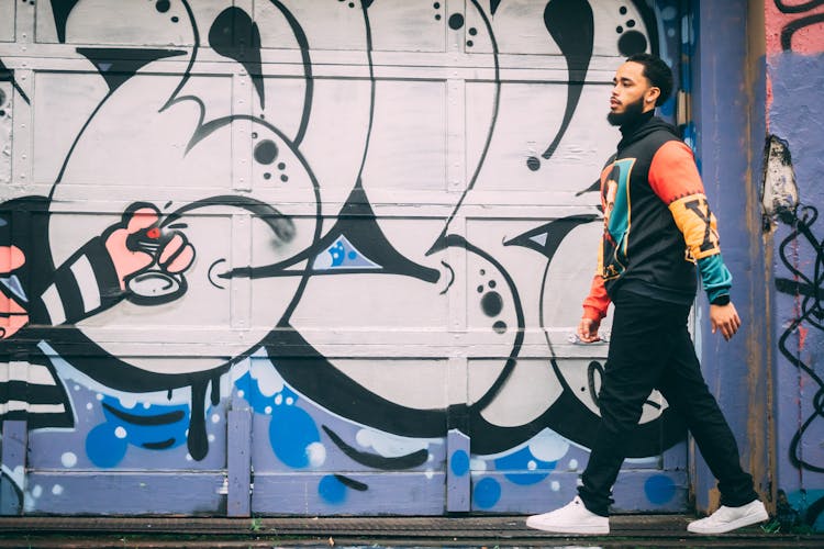 Man Walking With A Mural In The Background