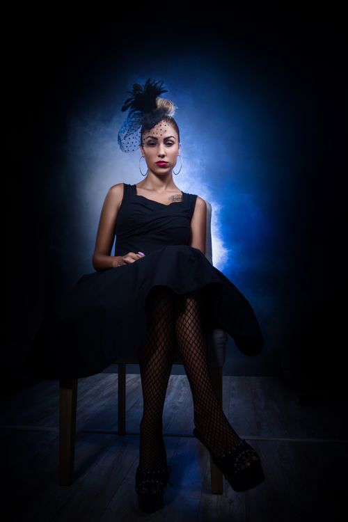 Free A fashionable woman poses in a dramatic, dark setting, emphasizing elegance and style. Stock Photo