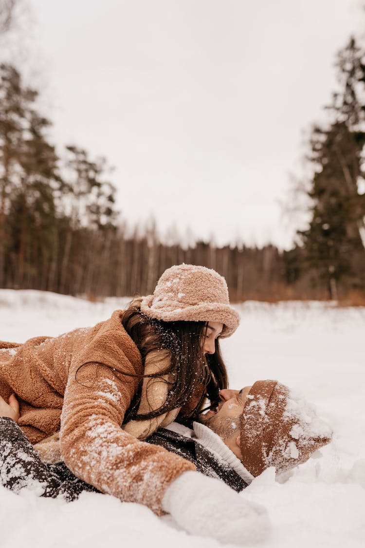 Young Couple Playing In The Snow On Top Of Each Other 