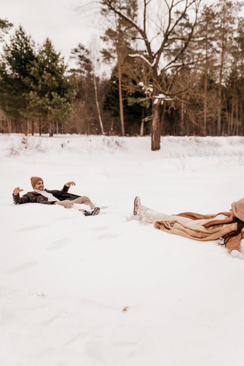 Free A happy young couple lying in the snow, enjoying a winter day outdoors. Stock Photo