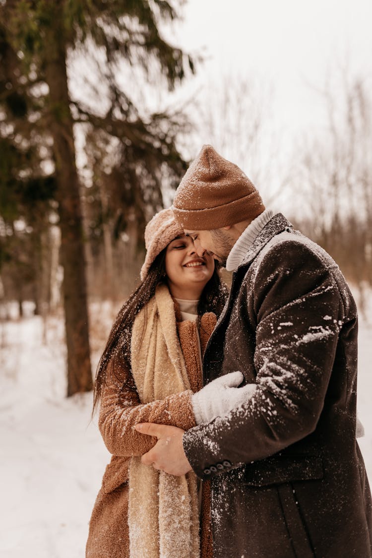 Young Couple Hugging In Winter Forrest 