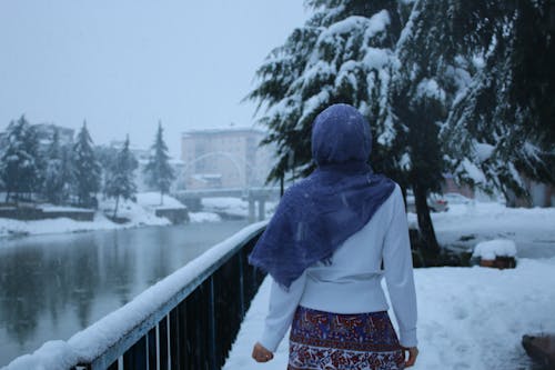 Free A Woman with Blue Headscarf Walking on Snow Stock Photo