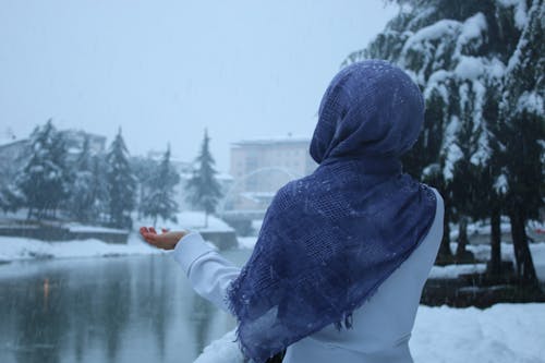 Free A Woman Catching Snowfall From the Sky Stock Photo