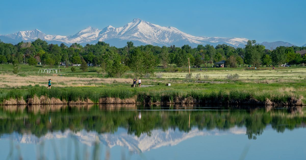 Beautiful landscape of mountains reflecting on a serene lake surrounded by lush greenery.