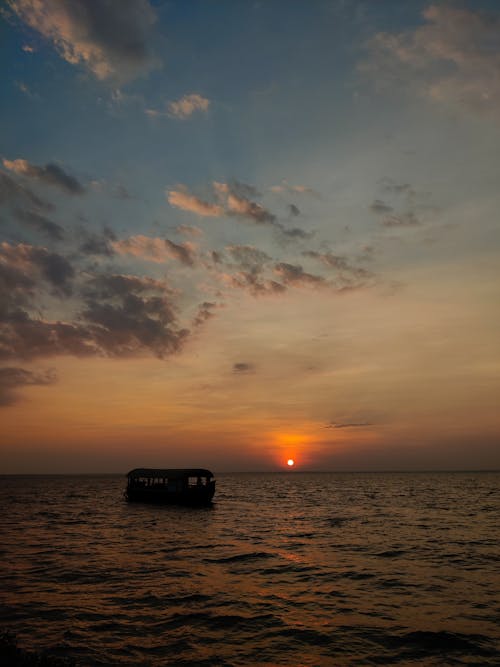 A Silhouette of a Boat at Sea during Sunset