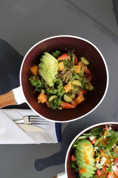 Top view of a vibrant avocado and vegetable salad served in a pan, perfect for a healthy meal.