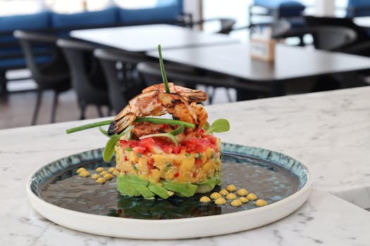 Colorful seafood tartare with shrimp and fresh vegetables presented on a ceramic plate in a restaurant setting.