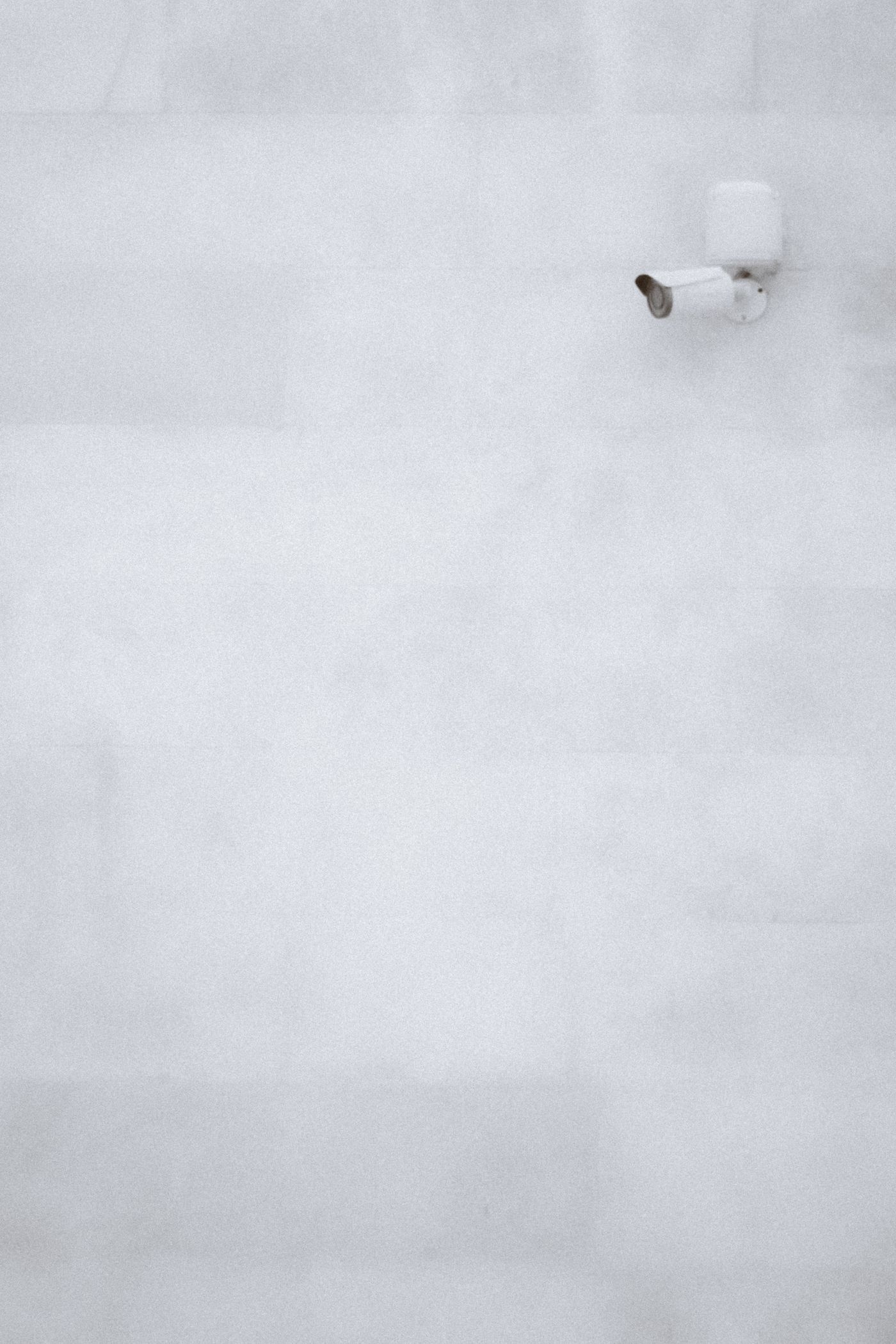 Caméra de surveillance blanche fixée sur un mur clair