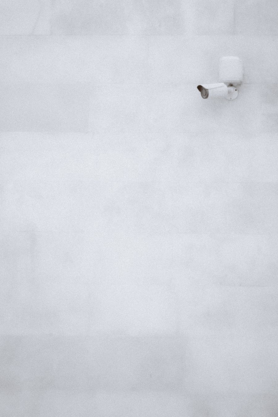 Caméra de surveillance blanche fixée sur un mur clair