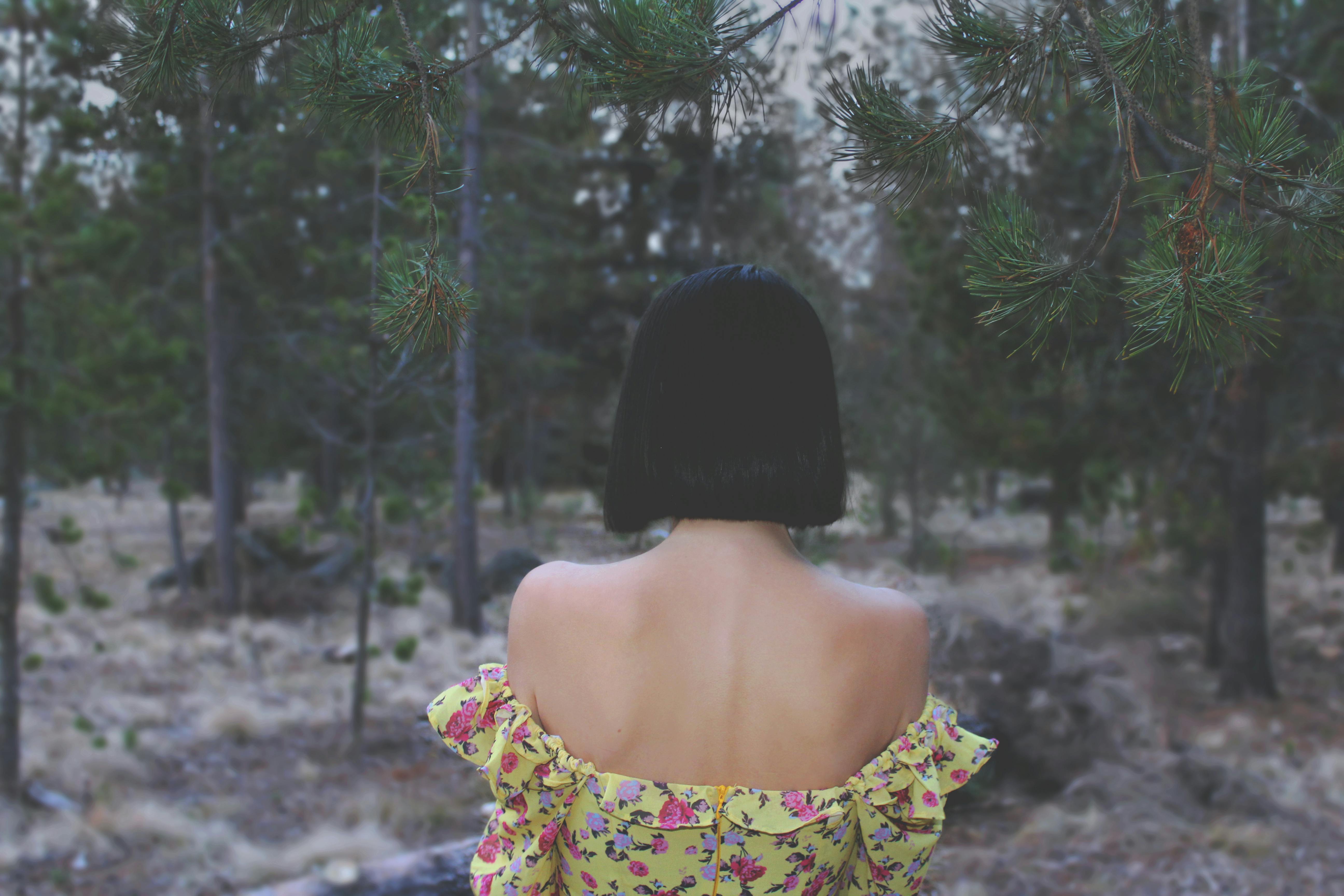 A woman in a floral dress stands in a forest in Bend, Oregon.